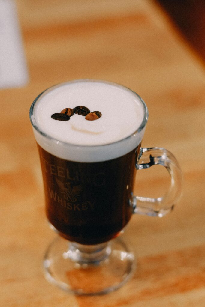 A classic Irish coffee with whipped cream and garnished with coffee beans, served in a glass mug.